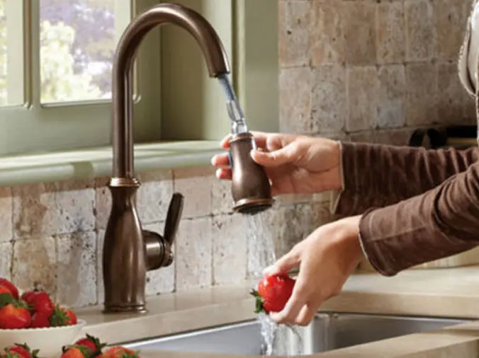 Wo=mans hands washing fruit in a kitchen sink