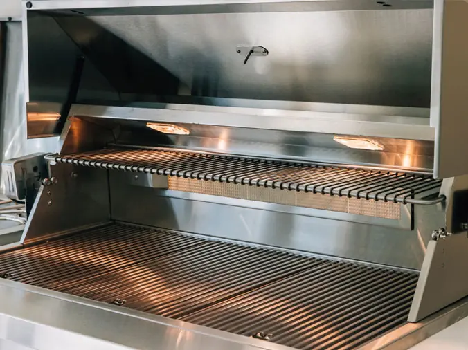 Stainless steel gas grill with lid open showing interior grilling area