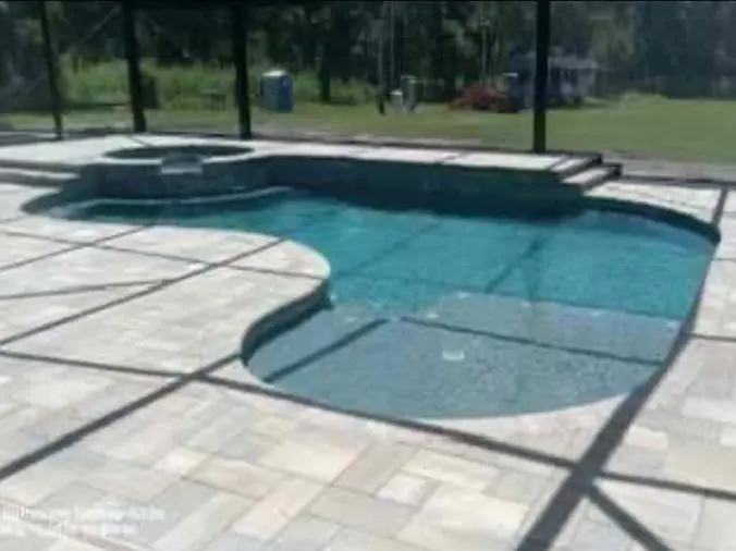 Oval swimming pool in backyard with glass enclosure
